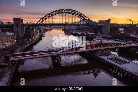 Newcastle, England, Regno Unito - 5 Febbraio 2019: Il sole sorge dietro l'iconica Tyne Bridge e ponte girevole tra Newcastle e Gateshead sul fiume T Foto Stock