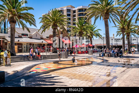 Il 31 dicembre 2018 , Glenelg Adelaide Australia del Sud : Moseley, vista piazza sul caldo giorno d'estate e di sole con bambini che giocano nella fontana di acqua in Glenelg. Foto Stock
