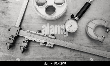 Metallo strumenti di misurazione su un tavolo di legno. Controllo di qualità del prodotto. In bianco e nero. Foto Stock