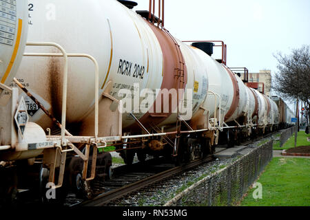 Treno merci con vetture di navi cisterna che passa attraverso il centro cittadino di Bryan, Texas, Stati Uniti d'America; trasporto chimico mediante vagoni ferroviari. Foto Stock