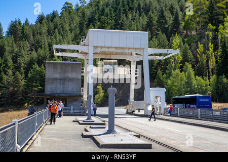 Turisti lasciano il loro tour bus alla sommità del Benmore diga per andare a prendere le foto della vista verso il basso al di sotto in Nuova Zelanda Foto Stock