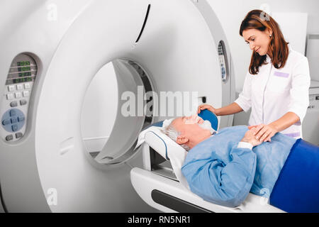 Gentile infermiera preparazione paziente anziano per CT scan in ospedale Foto Stock