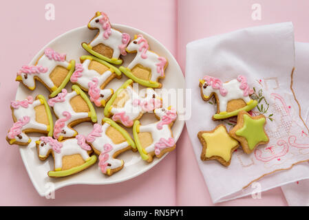 Unicorn zucchero a forma di cookie decorate con tonalità di glassa reale su sfondo rosa. Favole concetto. Vista dall'alto. Foto Stock