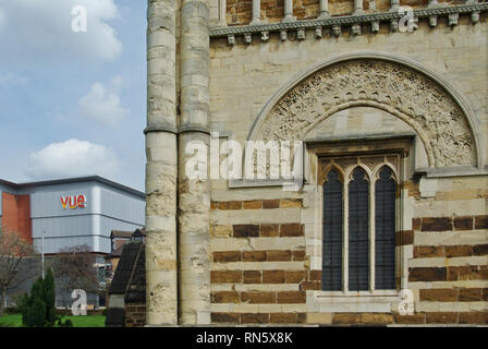 Antico e moderno, la torre normanna della chiesa di San Pietro e sullo sfondo la facciata del Vue Cinema; Northampton, Northamptonshire, Regno Unito Foto Stock