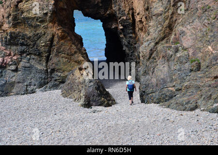 La donna gli escursionisti a piedi attraverso l'Arco Naturale nella scogliera di arenaria su Dixcart Bay sull'Isola di Sark, Isole del Canale, UK. Foto Stock