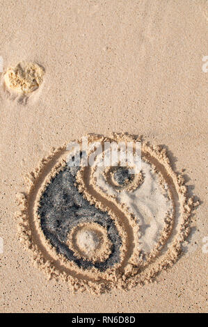 Yin-yang simbolo viene disegnato e riempito con sabbia nera e bianca a Melasti spiaggia di Bali, Indonesia Foto Stock