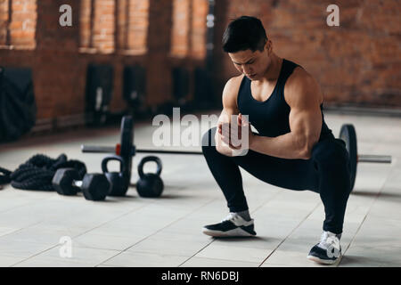 Amatuar sportivo muscolare facendo squat durante gli allenamenti al chiuso, uno stile di vita sano.hobby , copia spazio, croce montare Foto Stock