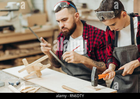 In falegnameria coworking studio i bambini e i ragazzi possono imparare una professione utile insieme con il papà. Ci sono classi di falegnameria per principianti in th Foto Stock