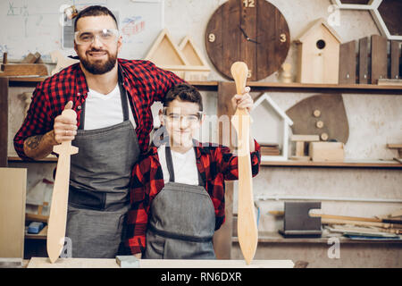 Relazioni familiari, la paternità, hobby, falegnameria, concetto di falegnameria - padre e figlio la riproduzione di cavalieri con legno spade DIY al workshop di falegname Foto Stock