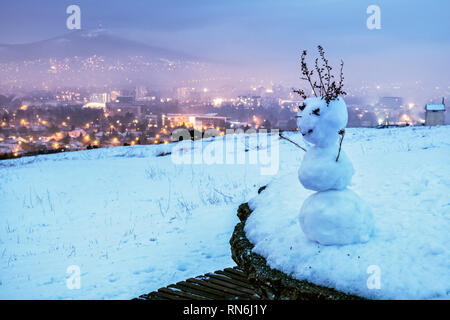 Divertente mini pupazzo di neve e di Nitra city, Repubblica slovacca. Sera scena d'inverno. Destinazione di viaggio. Foto Stock