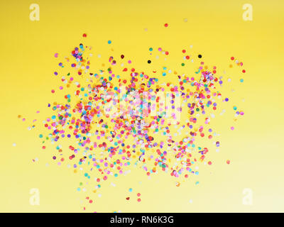 Coriandoli colorati su sfondo giallo come consistenza, concetto di vacanza. Foto Stock