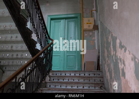 Periodo scala in legno per un blocco di appartamenti che conduce a una porta verde Foto Stock