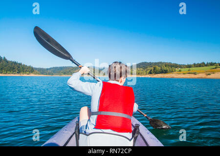 Giovane donna kayak sul lago di Lokve, nella regione di Gorski Kotar, Croazia. Avventurosa esperienza sportiva su una bella giornata di sole. Bellissimo lago blu. Foto Stock