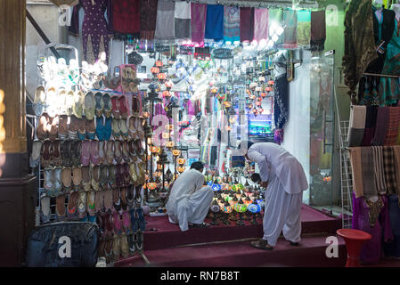 Dopo l'apertura del negozio per il business, un paio di commercianti di accensione di righe colorate lanterne arabe nel Vecchio Souk delle Spezie in Deira, Dubai in t Foto Stock