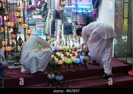 Dopo l'apertura del negozio per il business, un paio di commercianti di accensione di righe colorate lanterne arabe nel Vecchio Souk delle Spezie in Deira, Dubai in t Foto Stock