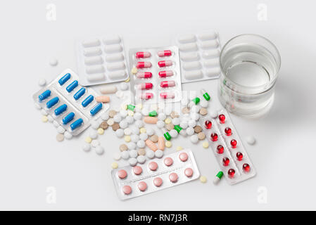 Medicina e salute. Pillole colorate con il bicchiere d'acqua. Vista dall'alto. Foto Stock