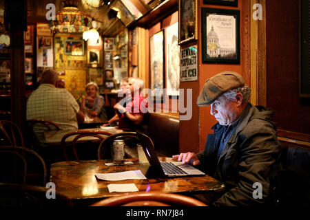 L uomo non identificato di bere e utilizza il suo computer in Vesubio Bar in San Francisco, CA Foto Stock