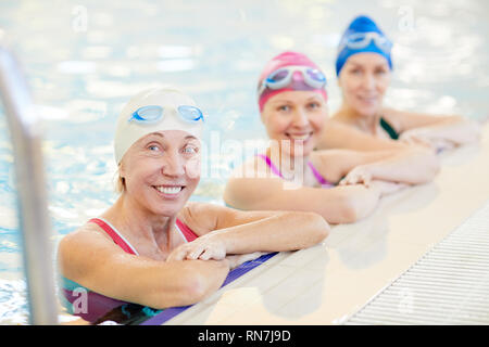 Tre donne mature che pongono in piscina Foto Stock