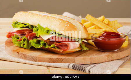 Sommergibile freschi sandwich con formaggio, pancetta, pomodori e lattuga, sulla luce sullo sfondo di legno Foto Stock