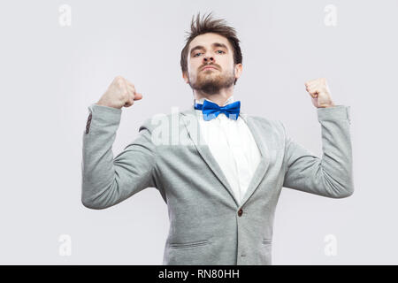 Io sono forti e indipendenti. Ritratto di soddisfatto orgoglioso bello uomo barbuto in casuale completo grigio e blu bow tie in piedi e guardando la telecamera ind. Foto Stock