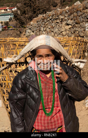 Il Nepal, Namche Bazaarm Sherpa donna con anello d'oro per il naso del cestello di trasporto sul fronte utilizzando tumpline Foto Stock