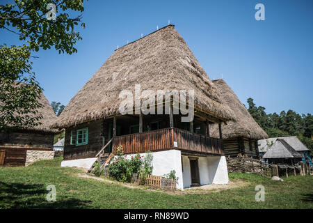 Tradizionale villaggio rumeno home con erba tetto di fieno in Folk Museum vicino a Sibiu. Foto Stock