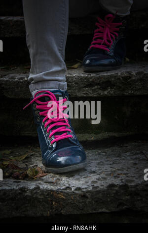 Gambe di Donne in nero scarpe con lacci rosa su scale. All'aperto, belle scarpe eleganti Foto Stock