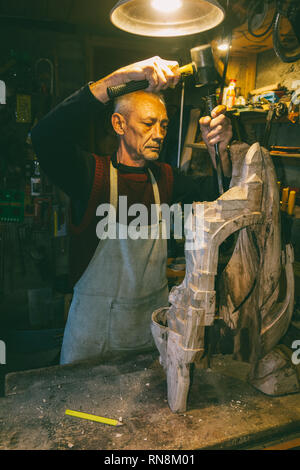 Maestro di legname 50 - 55 anni crea la scultura in legno in officina Foto Stock