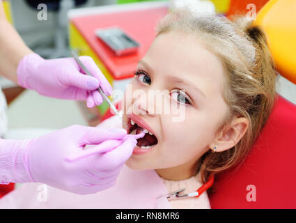 Il bambino è un dolce bambina senza frontale i denti di latte nel riunito dentale. Il dentista esamina i denti del bambino la paziente. Foto Stock