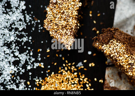 Il lusso artigianale di cioccolato fondente con seasame e sale marino, sfondo nero Foto Stock