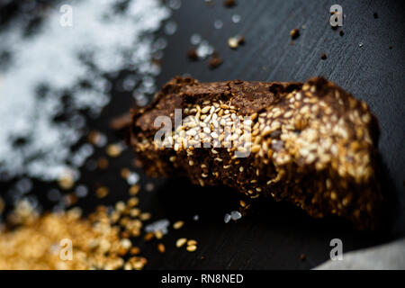 Il lusso artigianale di cioccolato fondente con seasame e sale marino, sfondo nero Foto Stock