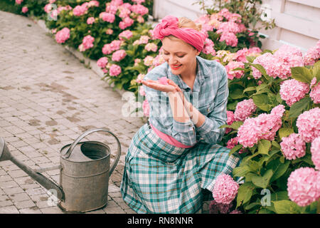 Ortensia. La primavera e l'estate. donna felice giardiniere con fiori. La cura dei fiori e irrigazione. suoli e fertilizzanti. donna cura dei fiori nel giardino Foto Stock