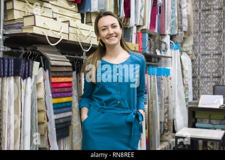 Ritratto di felice donna matura proprietario in tessuti interni store, sfondo campioni di tessuto. Small business home negozio di tessuti Foto Stock
