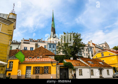 La guglia della medievale San Olaf la chiesa si erge al di sopra del villaggio di rivestimento per le antiche mura della città del Mar Baltico di Tallinn, Estonia. Foto Stock