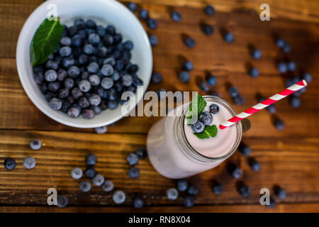 Frullato di mirtilli con foglia di menta e paglia sul tavolo di legno Foto Stock