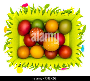 Stash di colorate uova pasquali dipinte di cera in un feltro di Pasqua cesto su sfondo bianco, isolata, vista dall'alto Foto Stock