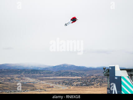 Un sciatore acrobatici sospesi in aria durante una pratica salto a Utah Olympic Park di Park City, Utah con Wasatch Mountains nella distanza Foto Stock