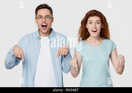 Stupiti felice coppia puntando le dita al di sotto di indicando un incredibile offerta di vendita Foto Stock
