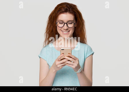 Felice giovane donna rosso in bicchieri tenendo il telefono cellulare Foto Stock