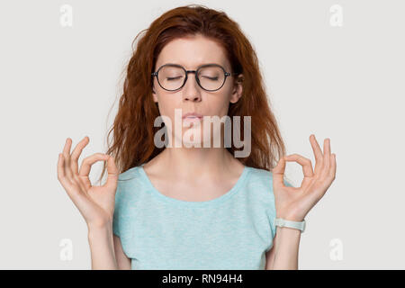 Sottolineato redhead donna meditando alleviare lo stress facendo esercizi di respirazione Foto Stock