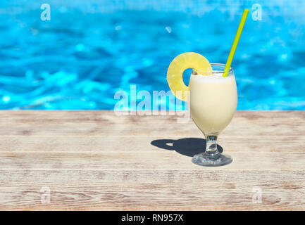 Bicchiere di cocktail pinacolada permanente sulla piscina listello in un resort tropicale Foto Stock