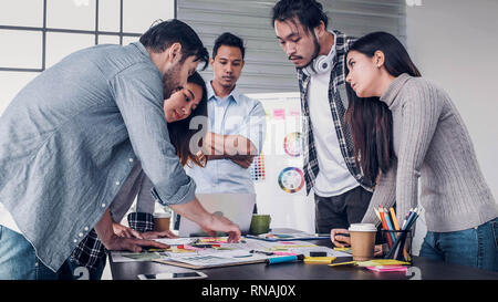 Il direttore creativo team di piombo brainstrom permanente di branding di progetto con team di designer al tavolo riunioni.La discussione idea creativa office,clap per mano Foto Stock