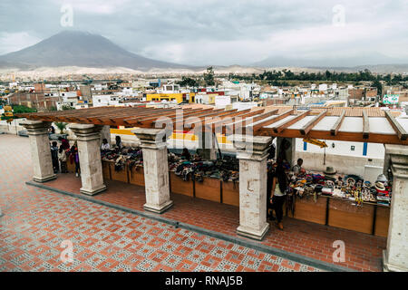 I fornitori di prodotti artigianali su di una piazza nella Città Bianca (Arequipa, Perù) con la città e il vulcano Misti in background. Foto Stock