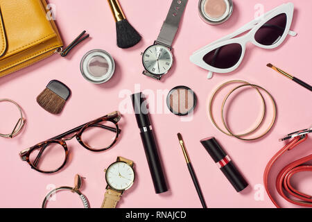 Vista dall'alto di orologi, rossetto, orecchini, occhiali, occhiali da sole, borsa, ombretto, blush, cinghia, spazzole cosmetiche, braccialetti e mascara Foto Stock