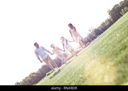 Famiglia a piedi. Famiglia di quattro camminando sul campo erboso comunicante sorridendo felice Foto Stock