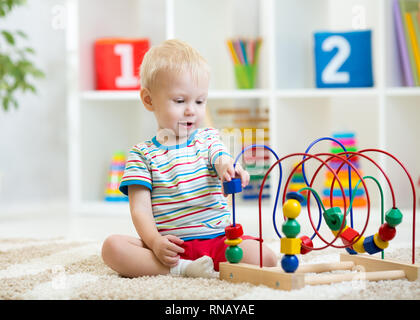 Preschooler bambino ragazzo giocando con il giocattolo di sviluppo. I bambini giocano con toy cordoni in asilo nido o asilo nido. Bimbo Baby nella nursery room. Foto Stock