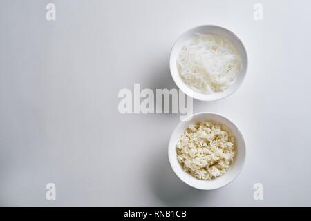 Piastre in vetro con pasta e riso bollito. piatto, vista dall'alto, sfondo bianco Foto Stock