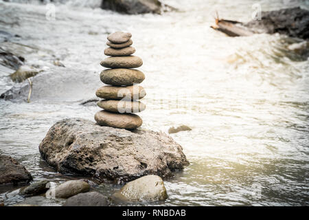 Pietre di bilanciamento su una roccia di fiume. Il concetto di stabilità in un mondo di turbolenza Foto Stock