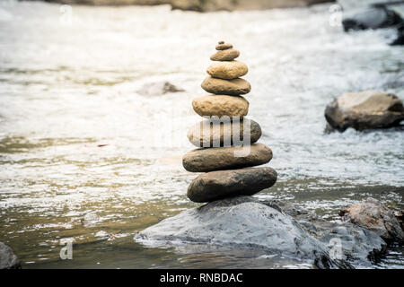 Pietre di bilanciamento su una roccia di fiume. Il concetto di stabilità in un mondo di turbolenza Foto Stock