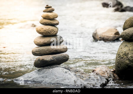 Pietre di bilanciamento su una roccia di fiume. Il concetto di stabilità in un mondo di turbolenza Foto Stock